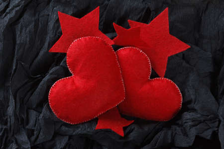 Love concept, red hearts and stars on black paper texture. Dark background with two felt hearts for use in graphic design. Valentine's style, St. Valentine's Day.の写真素材