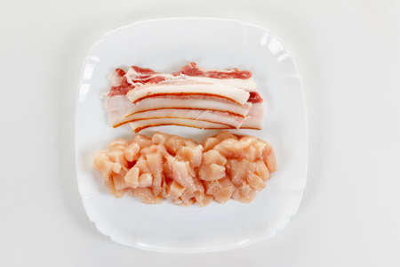 raw chicken and pork bacon meat on white plateの写真素材