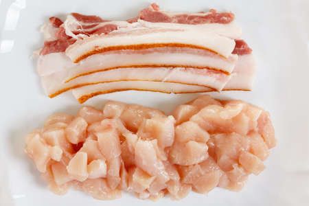 raw chicken and pork bacon meat on white plateの写真素材