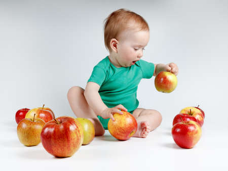 Adorable child with apples sitting on white background