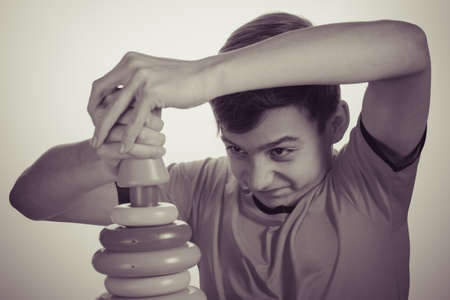 Caucasian boy playing with a toy pyramid. Old advertising concept, development of teenagers. Photo in vintage style of old picturesの写真素材