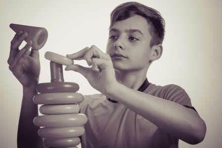 Caucasian boy playing with a toy pyramid. Old advertising concept, development of teenagers. Photo in vintage style of old picturesの写真素材