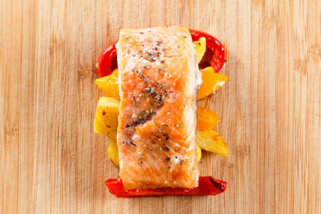 Baked prepared salmon fillet with vegetables, spices and arugula on a cutting board closeup. Cooking fishの写真素材