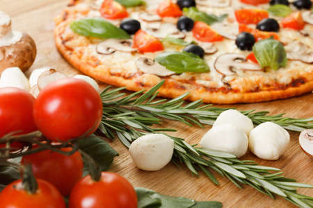 Pizza with mushrooms, olives and tomatoes. Basil, rosemary and fresh vegetables. Freshly homemadeの写真素材