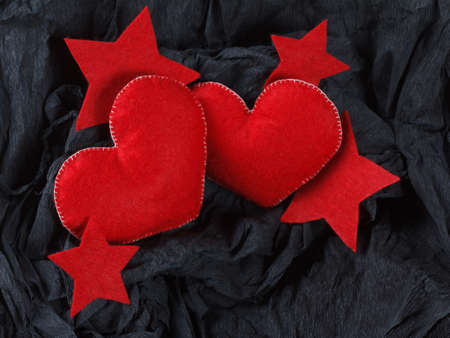 Love concept, red hearts and stars on black paper texture. Dark background with two felt hearts for use in graphic design. Valentine's style, St. Valentine's Day.の写真素材