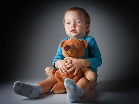 Little boy hugging a teddy bear in studioの写真素材