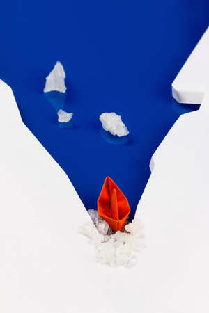 Origami paper boat on water as an icebreaker, ice punched. Concept of success, moving forward, overcoming difficultiesの写真素材