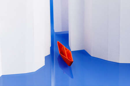 Origami paper boat on water as an icebreaker, ice punched. Concept of success, moving forward, overcoming difficultiesの写真素材