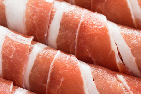 Slices of bacon roll closeup background, cooking foodの写真素材