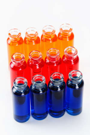 Blue, red and orange liquid in chemical lab test tubes. Closeup background on whiteの写真素材