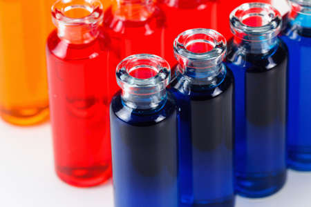 Blue, red and orange liquid in chemical lab test tubes. Closeup background on whiteの写真素材