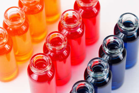 Blue, red and orange liquid in chemical lab test tubes. Closeup background on whiteの写真素材