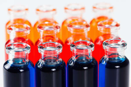 Blue, red and orange liquid in chemical lab test tubes. Closeup background on whiteの写真素材