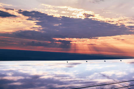 Unusual reflection of sky and clouds on the wing of an airplane, top viewの写真素材