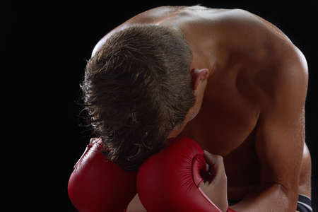 Young boy athlete, boxer or kickboxer gloves after losing or training. Black background.の写真素材
