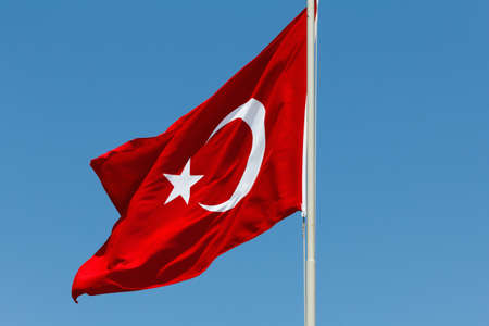 Red Turkish flag with a star and crescent on a blue skyの写真素材
