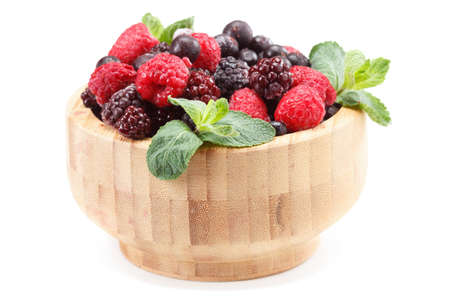Frozen berries in wooden bowl, covered with ice with mint leaves closeup. Isolated on white