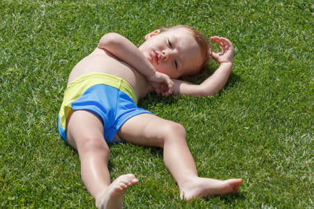 Little boy lies on the grass lawn in summer parkの写真素材