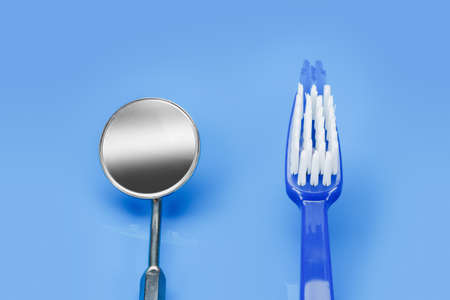 Tools dentifrice. Mirror dentist and a toothbrush on a blue backgroundの写真素材