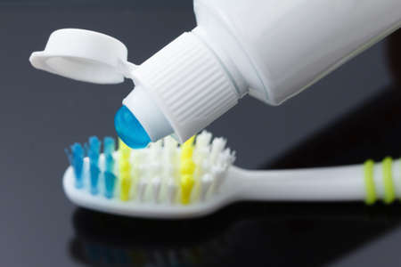Toothbrush against on black background with tube toothpaste and reflection