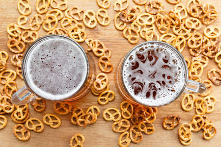 Mug of cold foamy beer with brezel. Overhead view. Traditional german Oktoberfest snacks and beer on wooden backgroundの写真素材