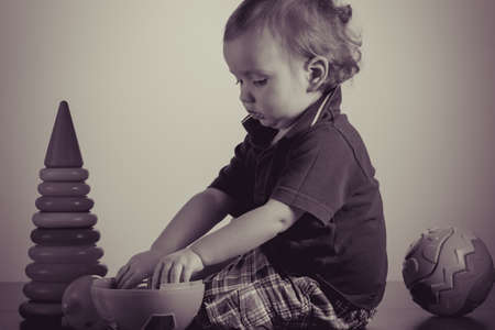Caucasian baby playing with a toy pyramid. Photo in vintage style of old picturesの写真素材
