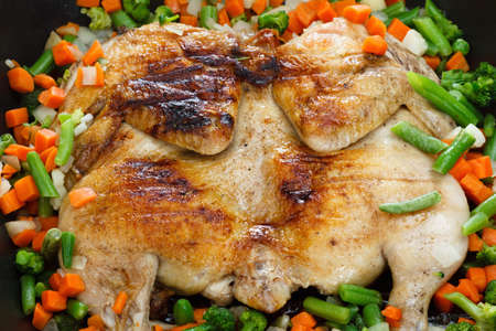Whole grilled chicken with vegetables, cooked in a frying panの写真素材