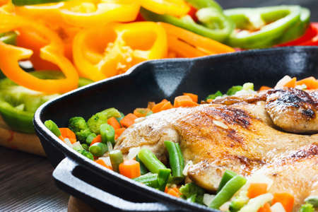 Whole grilled chicken on a grill pan fried with vegetables and bell pepperの写真素材