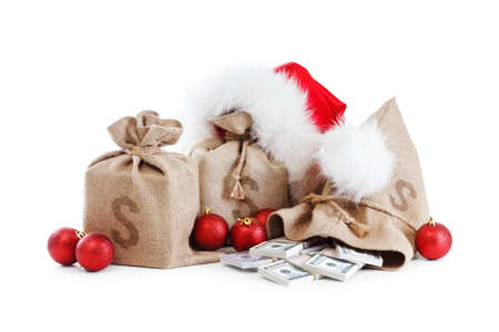 Christmas gift isolated on white background. Concept with money bag, santa claus cap. Stack of dollar currency.の写真素材