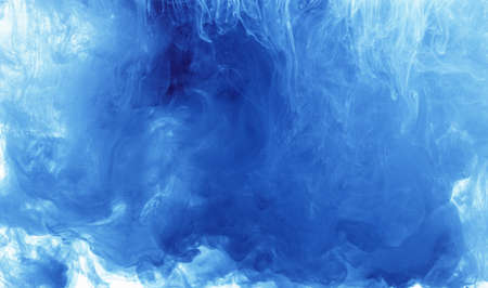 Abstract background color ink drop in water, motion swirling. Blue cloud of paint on white.の写真素材