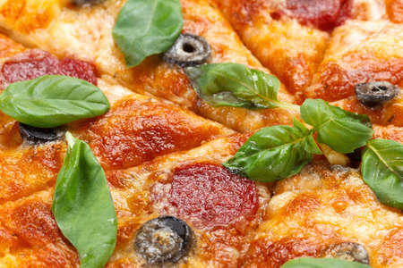 Hot pizza slices with salami and olives, melting cheese on a rustic wooden table as backgroundの写真素材
