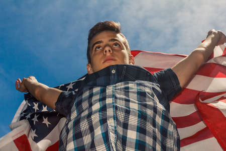 USA flag is held by a running guy in the background of a summer sky Outdoorの写真素材