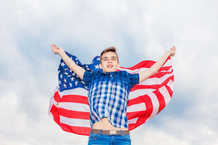 USA flag is held by a running guy in the background of a summer sky Outdoorの写真素材