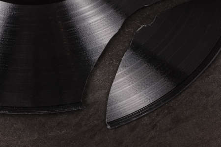 Broken vinyl record on a textured metal surfaceの写真素材
