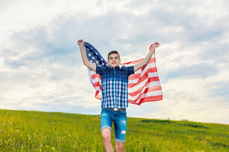 USA flag is held by a running guy in the background of a summer sky Outdoorの写真素材