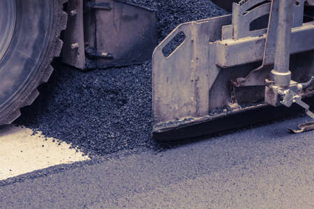 Paver makes the new asphalt on the road. Roadwork with heavy machinery.の写真素材