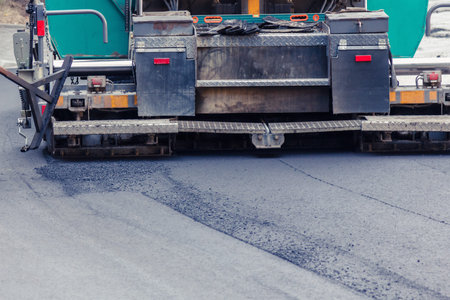 Paver makes the new asphalt on the road. Roadwork with heavy machinery.の写真素材