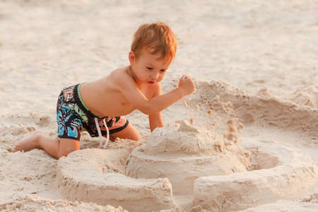 Kid destroy the sand castle stand on the beach.の写真素材