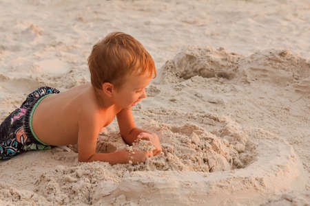 Kid destroy the sand castle stand on the beach.の写真素材