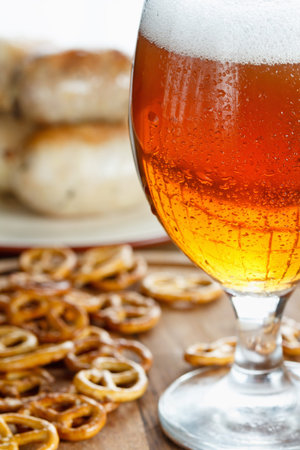 Traditional snacks and beer Oktoberfest. A glass of cold foamy beer with pretzels and grilled sausages on a wooden backgroundの写真素材