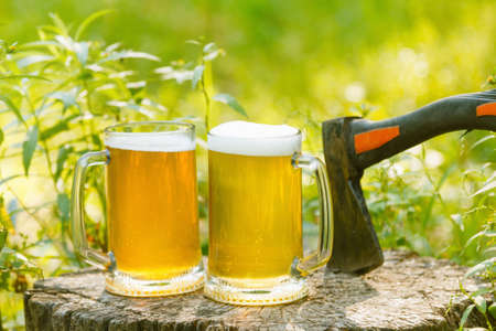Mugs with beer octoberfest picnic or party on natural background with axe.の写真素材