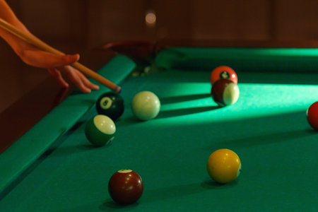 Playing man by cue in billiard pool close-up balls bar.