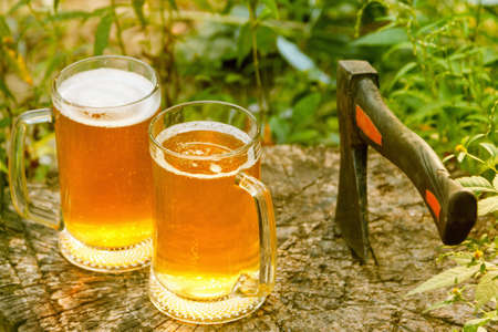 Beer mugs cheers, picnic or party on natural background with axe, top viewの写真素材