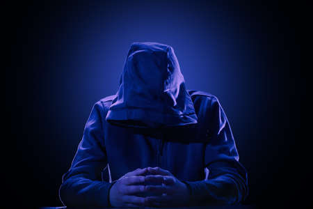 Hacker in a hood on black background. The violation of intellectual property rights conceptの写真素材