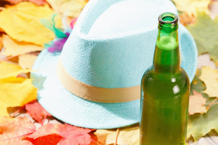 Bottle of Beer glass pint octoberfest picnic on natural background with hat and autumn yellow leaves