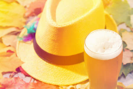 Beer glass pint octoberfest picnic on natural background with hat and autumn yellow leavesの写真素材