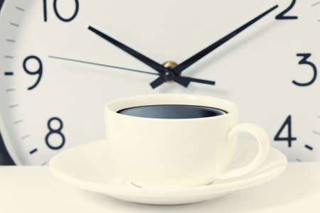 time for a coffee break during work with coffee cup and clock at ten o clock isolated on whiteの写真素材