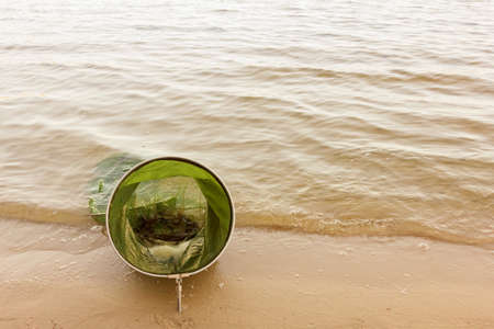 Fishing rods and fishing gear on the river bank, lake coast close up wave.の写真素材
