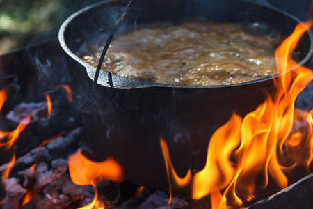 Tourist bowler with food on bonfire, cooking in the hike, outdoor activities. Preparation of pilaf or soup on fire.の写真素材
