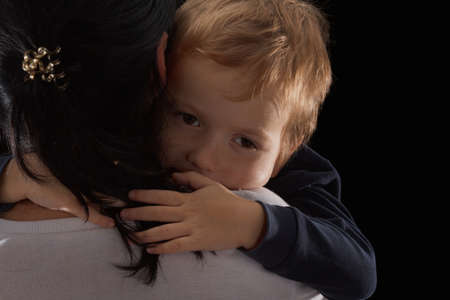 Adoption concept, an orphan is a little boy and his new mother. Happy childhood, caring for children. Sad boy on black backgroundの写真素材